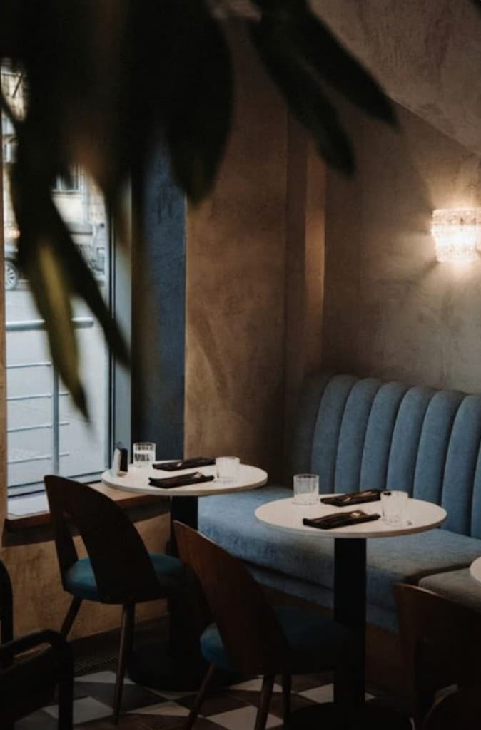 Intérieur de restaurant : salle cosy, banquettes bleues et tables dressées